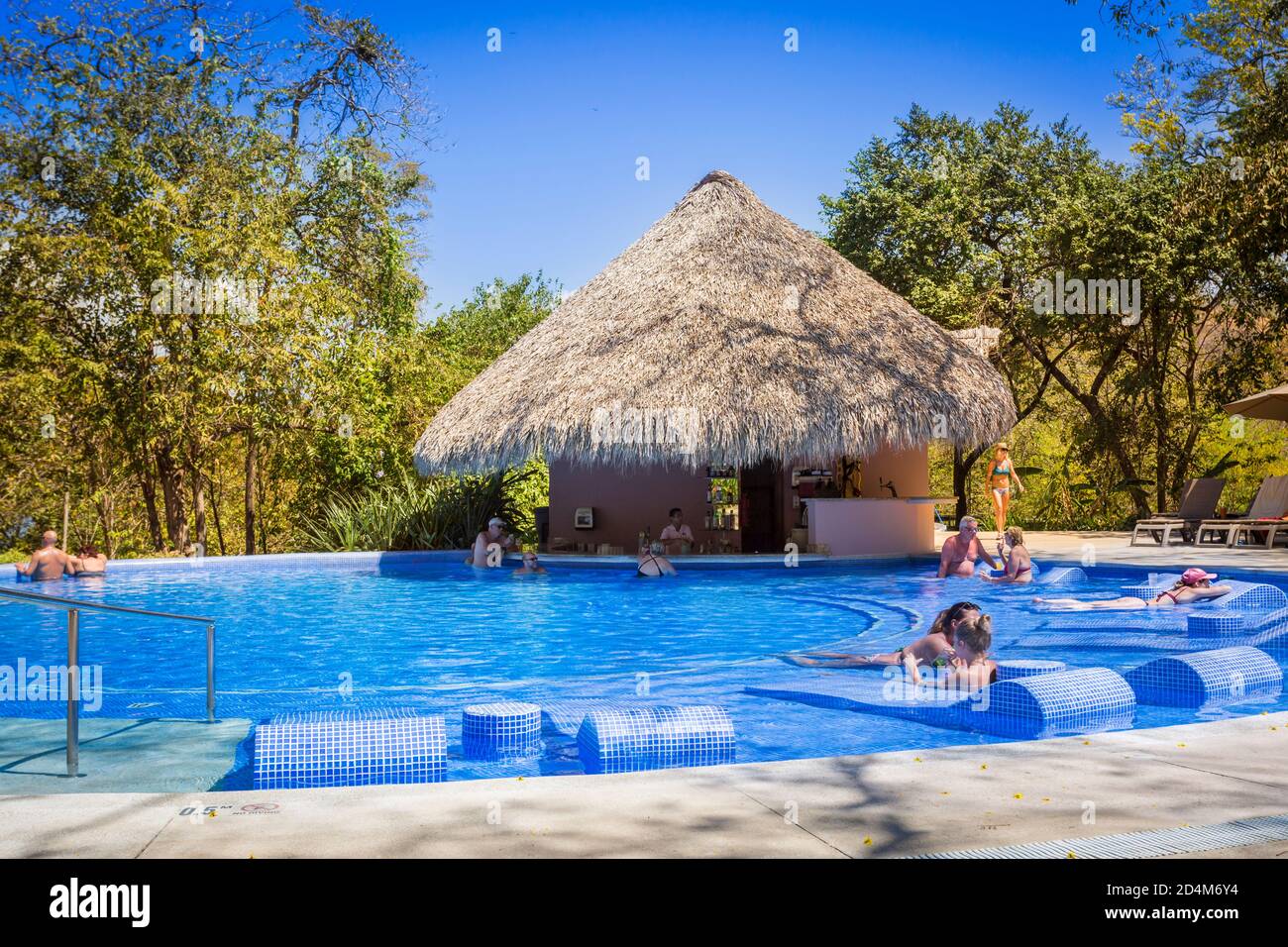 tourists at poolside bar with thatched roof, Occidental Papagayo Hotel, Guanacaste; Costa Rica; Central America Stock Photo