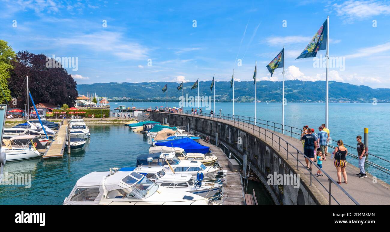 Lindau, Germany - July 19, 2019: Panorama of Lake Constance or Bodensee, people walk next to yachts in harbor. This old town is tourist attraction of Stock Photo