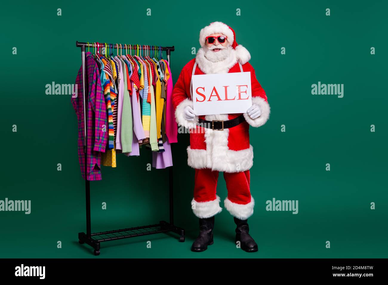 Full length body size view of his he nice fat funny cheerful bearded glad Santa selling outlet season clothes holding in hands poster bargain garment Stock Photo