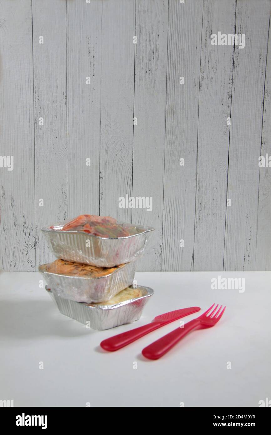 https://c8.alamy.com/comp/2D4M9YR/delivery-menu-concept-pile-of-foil-boxes-knife-and-fork-on-white-background-against-wooden-background-take-away-of-organic-daily-meal-copy-space-2D4M9YR.jpg