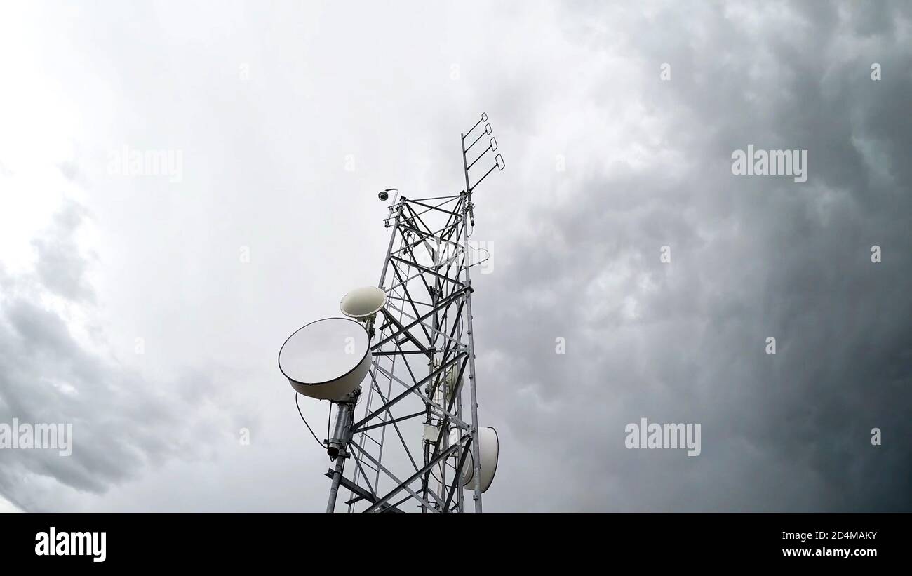 Radio antenna tower telecommunication against cloudy white sky in low angle view. Isolated background. Stock Photo