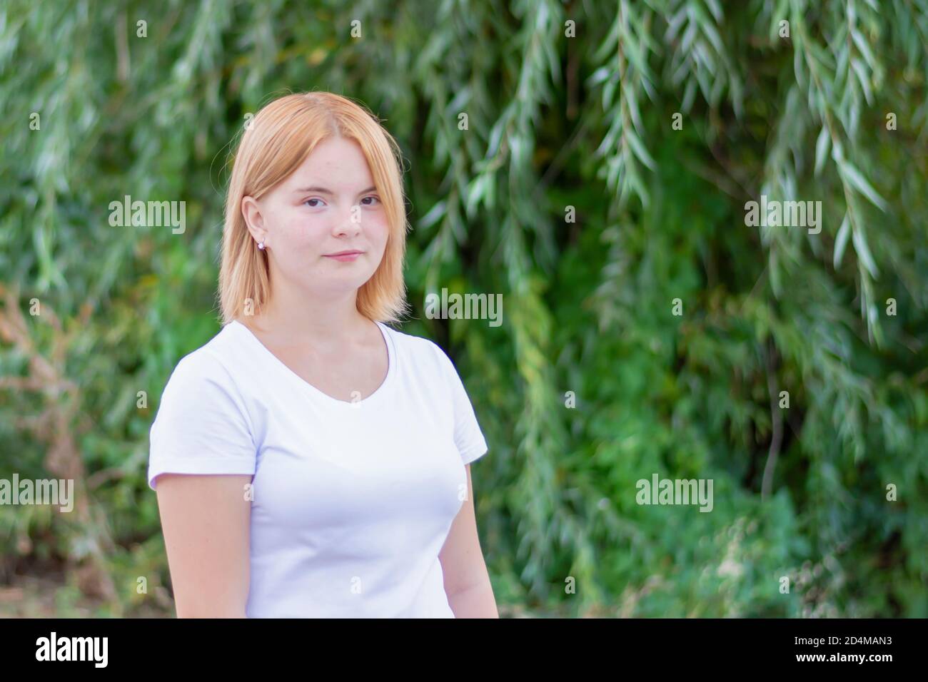 Young beautiful blonde woman in summer park. Close-up, blurred background. Stock Photo