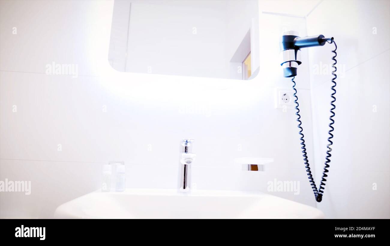 White bathroom sink and mirror with Hair Dryer in a hotel bathroom background concept. Stock Photo