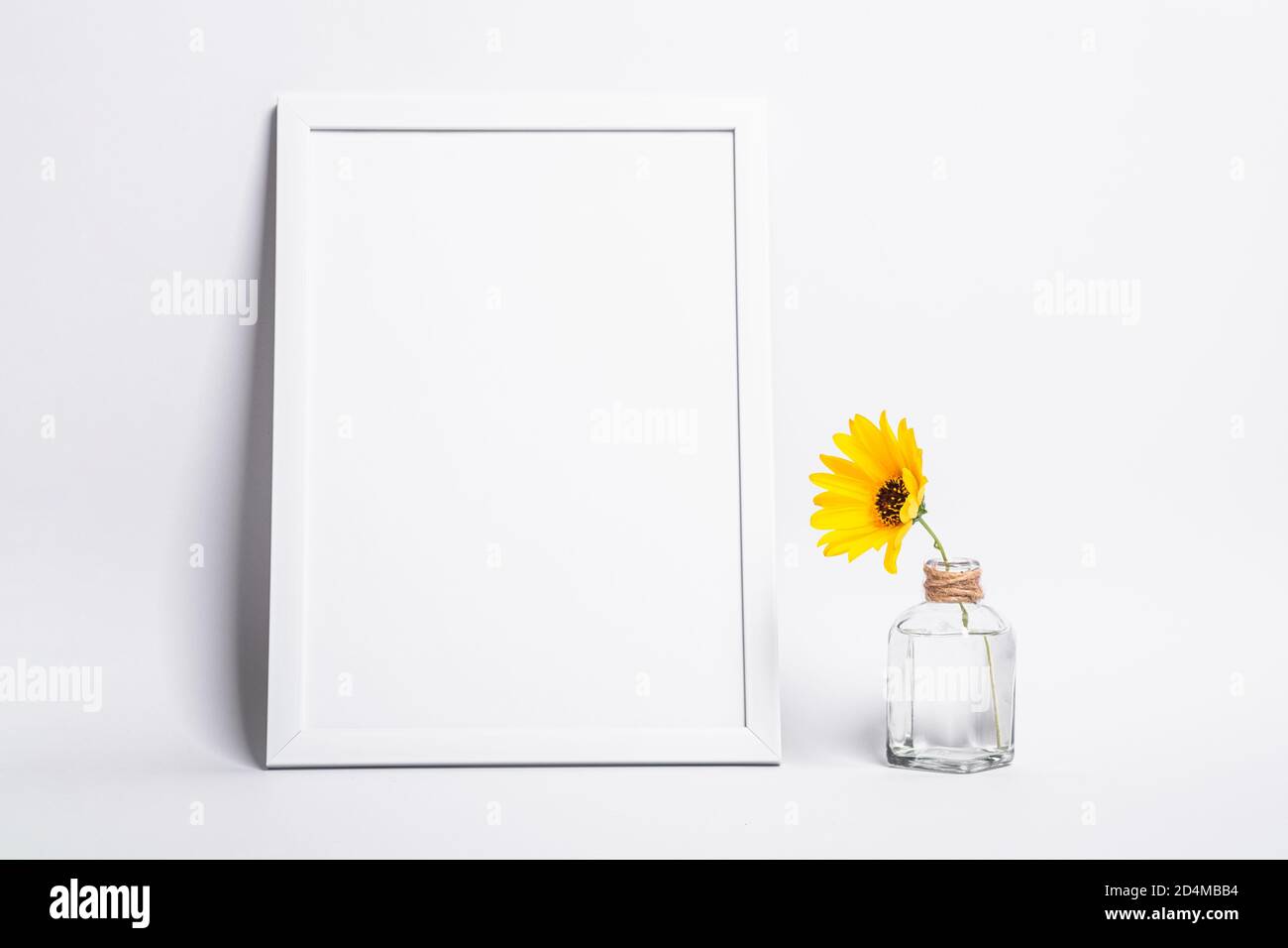 White empty picture frame mock up with yellow flower in glass jar Stock Photo