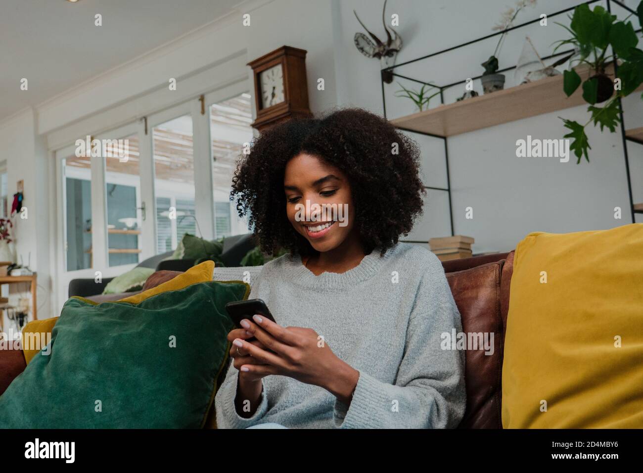 Woman sitting on the couch browsing cellular, smiling at text message ...