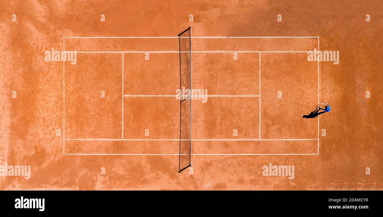 View from above, aerial view of a person playing tennis on a clay court during the Coronavirus (Covid-19) outbreak. Stock Photo