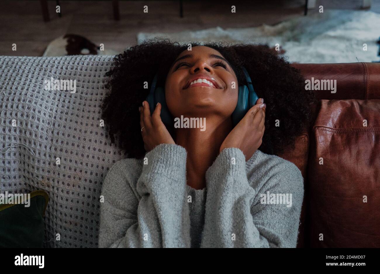 Beautiful young woman happily listening to music on headphones in the lounge Stock Photo