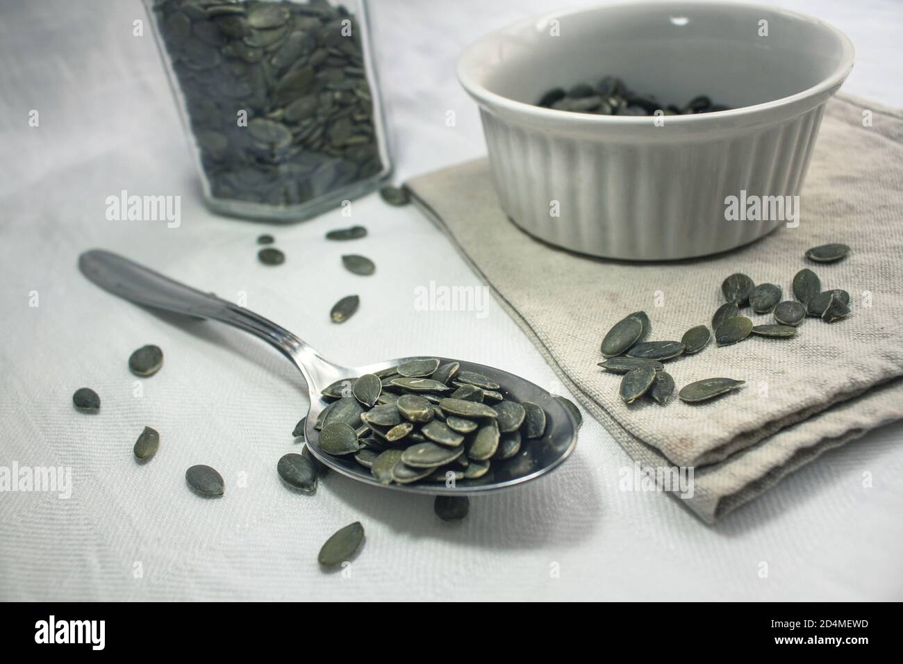 A heaping spoonful of pumpkin seeds on a white tablecloth Stock Photo