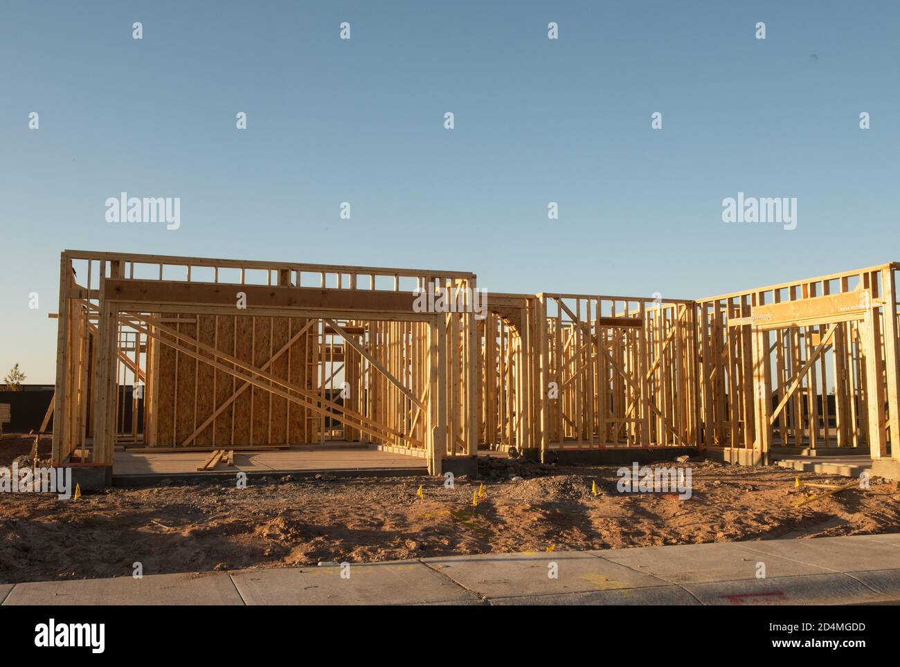 A partial view of a new house construction showing the wood frame before the siding and roofing stands in early morning light on a dirt lot, horizontal view. Stock Photo