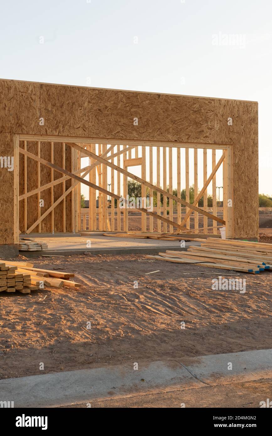 A partial view of a new house construction showing the wood frame before the siding and roofing stands in early morning light on a dirt lot, vertical view. Stock Photo