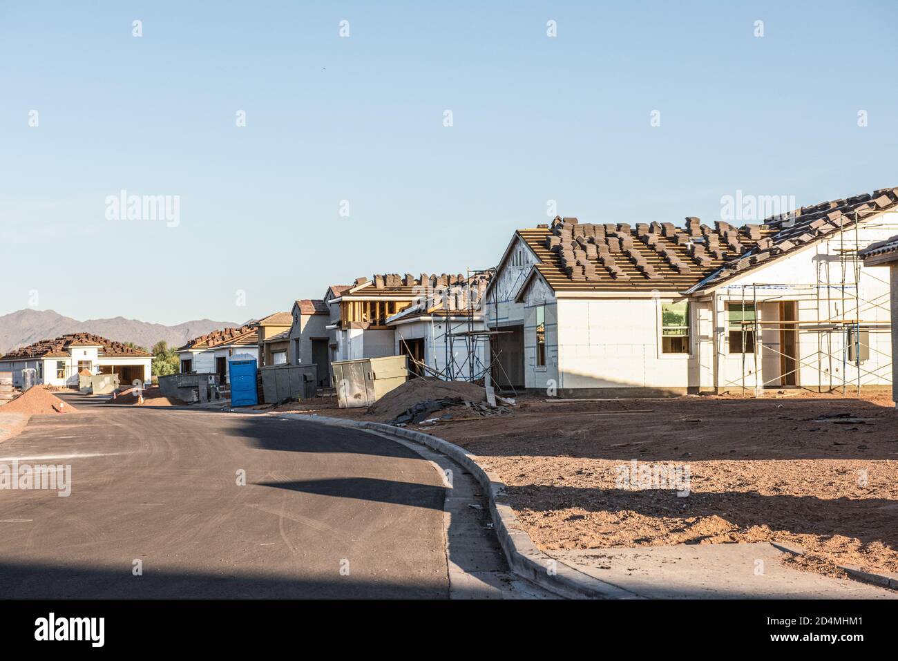 A row of new houses, being constructed during Arizona building boom, stands in early morning light on a dirt lot, horizontal view. Stock Photo