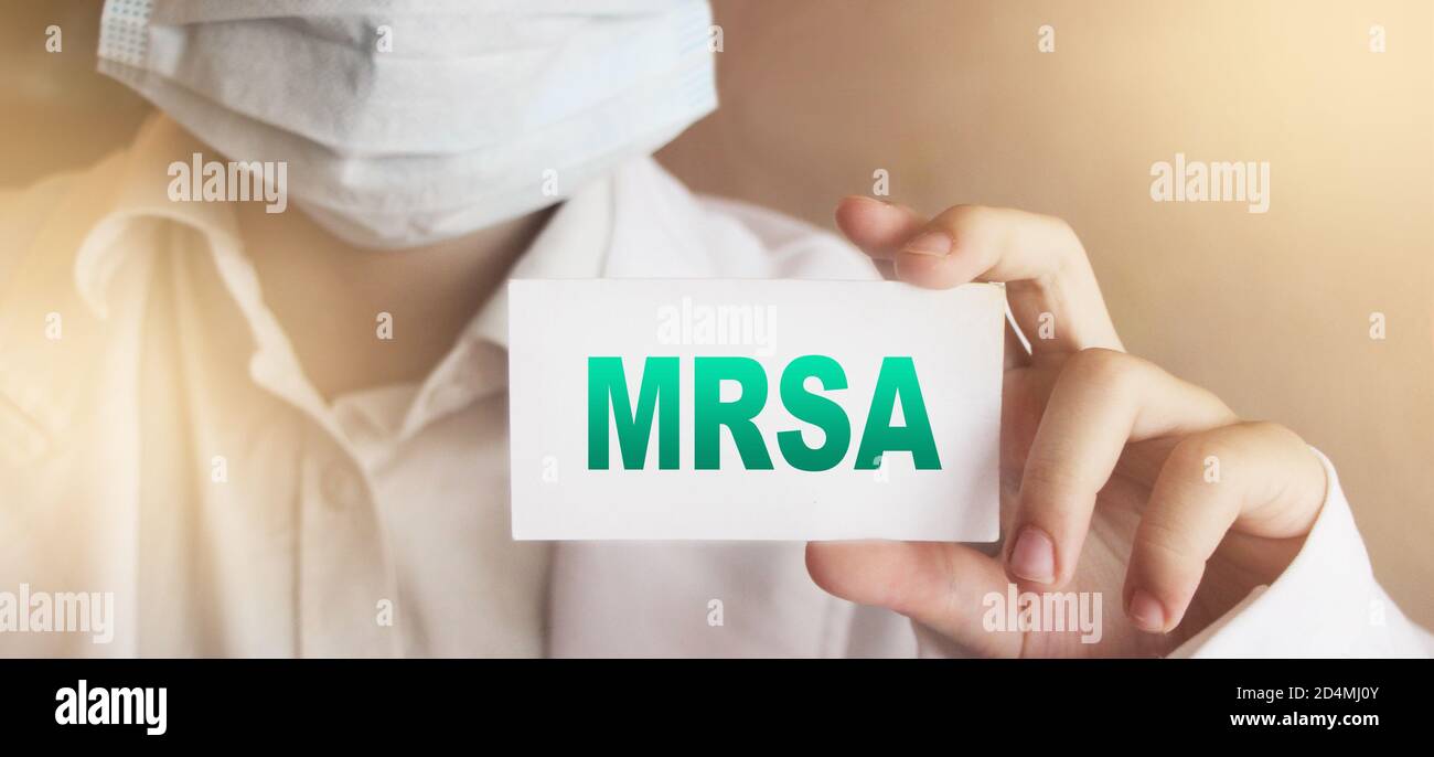 Doctor,wearing face protective mask shows a card with the text MRSA