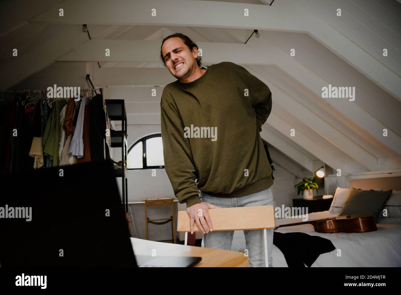 Young professional male with back pain while working from home in his