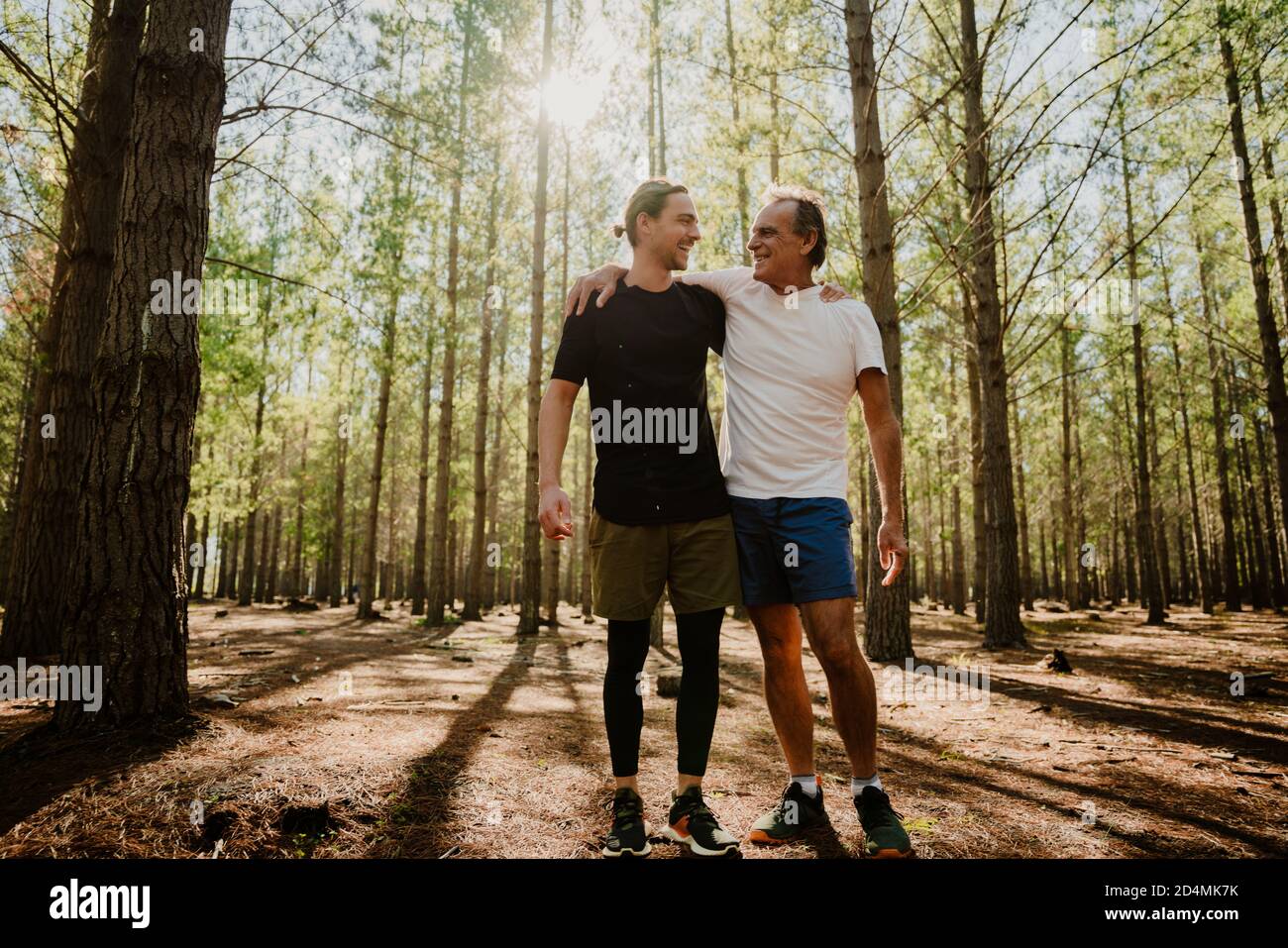 Caucasian father and son embracing after a run together in the woods ...