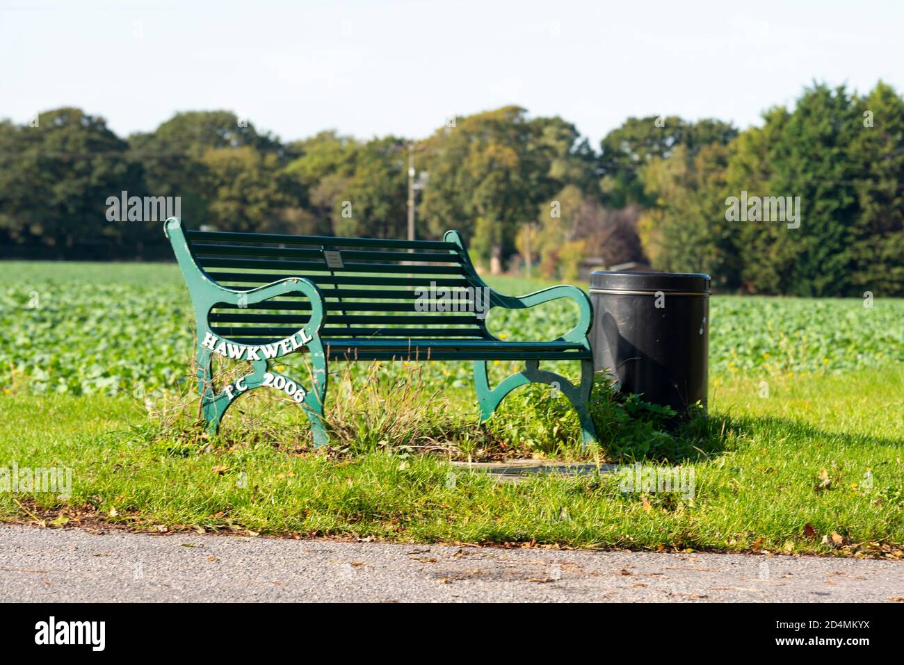 Metal bench on the edge of a field, marked with Hawkwell Parish Council 2006. Bin Stock Photo