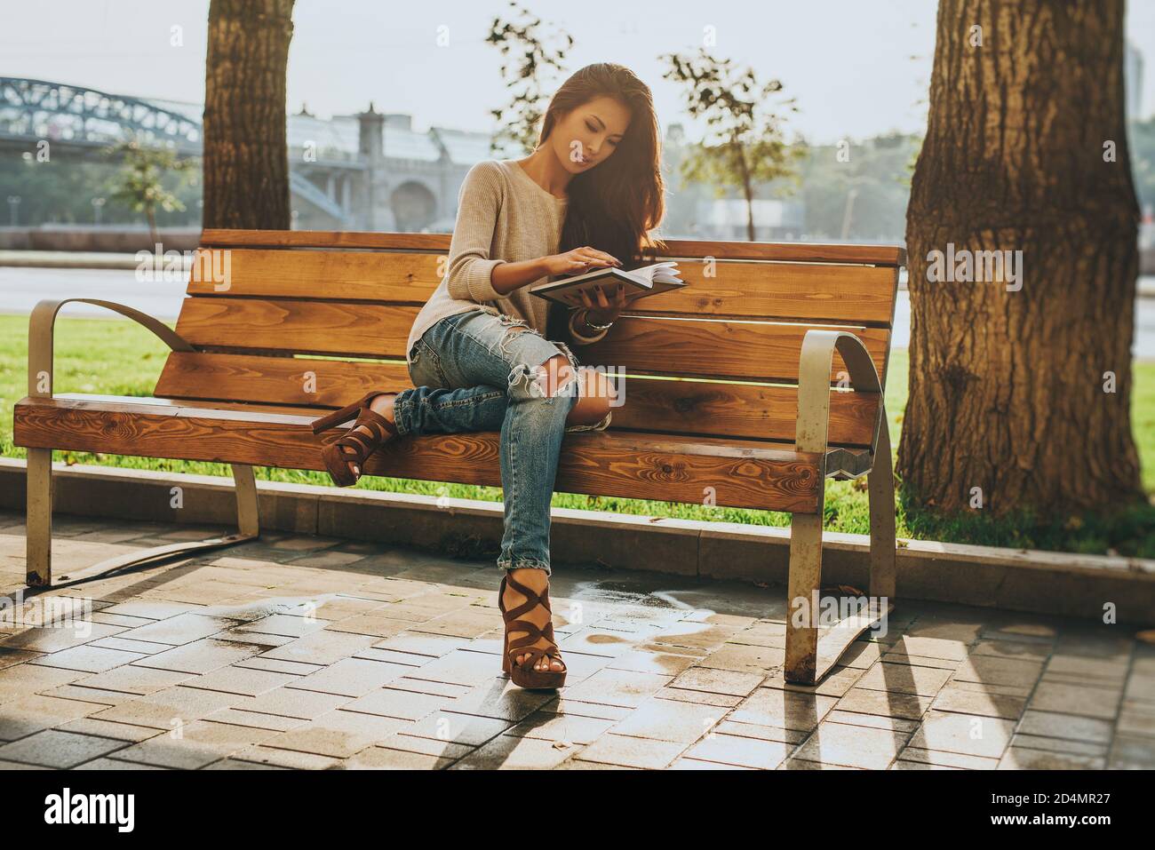 Young beauty and fashion asian woman sitting on bench in city and reading book Stock Photo