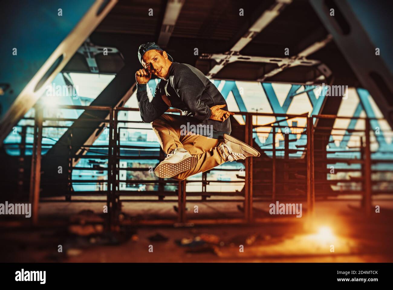 Young cool man break dancer jumping. Urban bridge with cool and warm lights background. Stock Photo