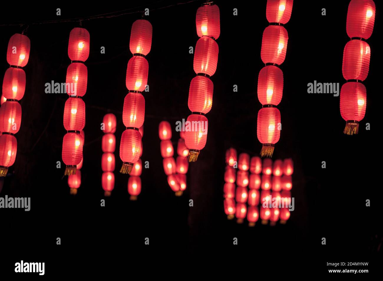 Red chinese paper lanterns lit in during a dark evening. Such lanterns are a tradition in China and Asia for the Chinese New Year.  Red chinese new ye Stock Photo