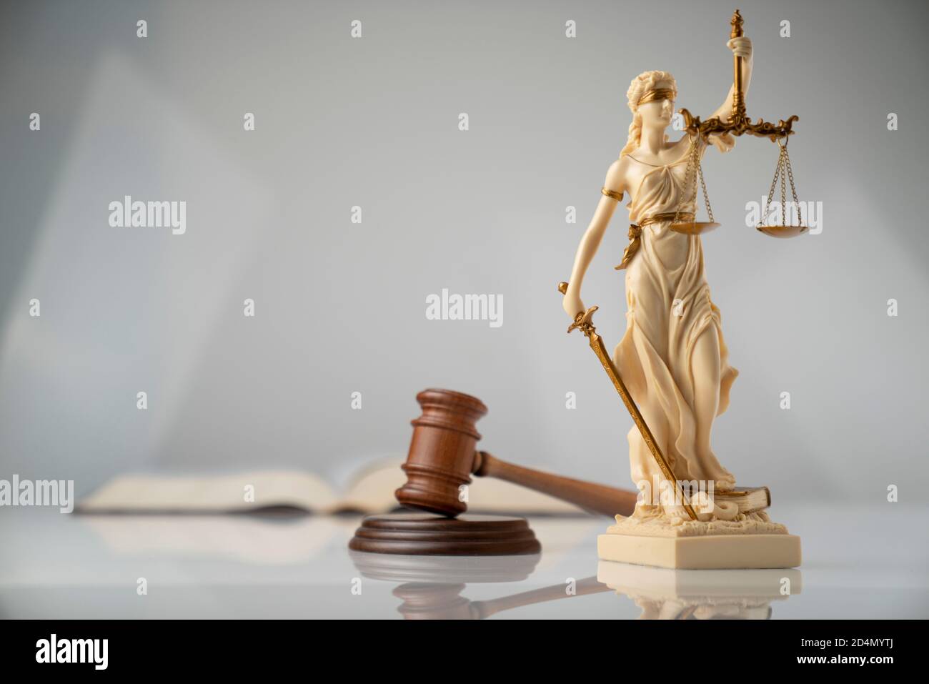 Law symbols composition. Themis statue, judge’s gavel and scale of justice on white table on off