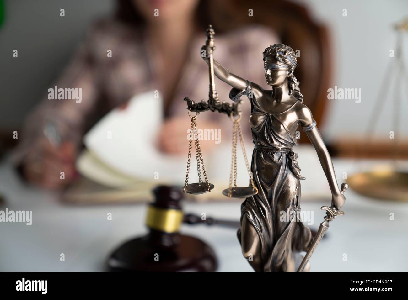 Female attorney at work. Judge's gavel and Themis statue on white desk. Stock Photo