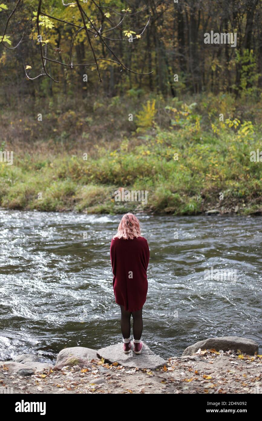 A girl with pink hair standing next to a river. Stock Photo