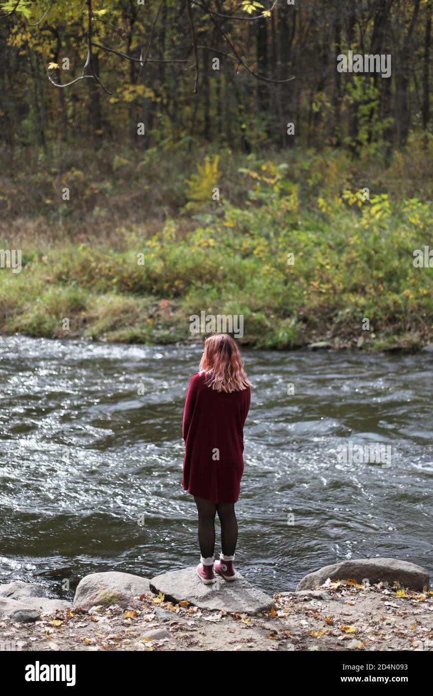 A girl with pink hair standing next to a river. Stock Photo