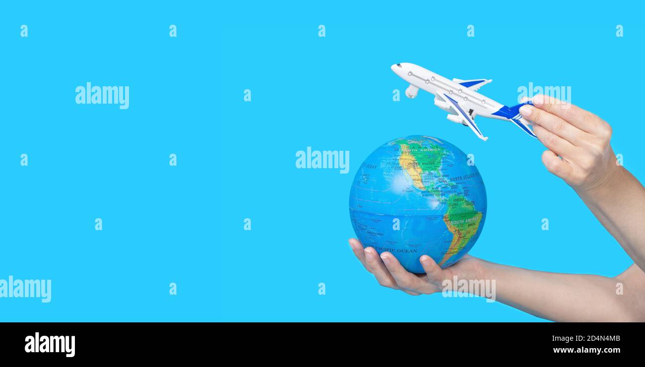 Travel concept. Female hands holding globe and figurine of passenger plane on blue background. The plane is flying to the globe. Stock Photo