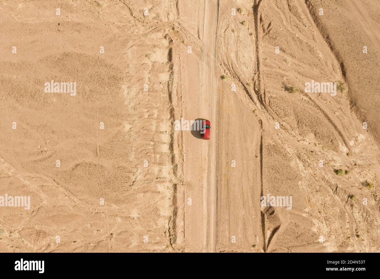 Red SUV on a desert path, high altitude aerial image. Stock Photo