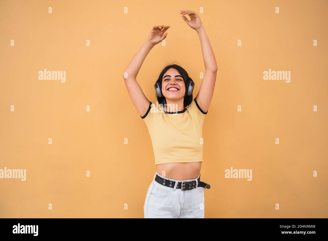 Portrait of young latin woman listening to music with headphones ...