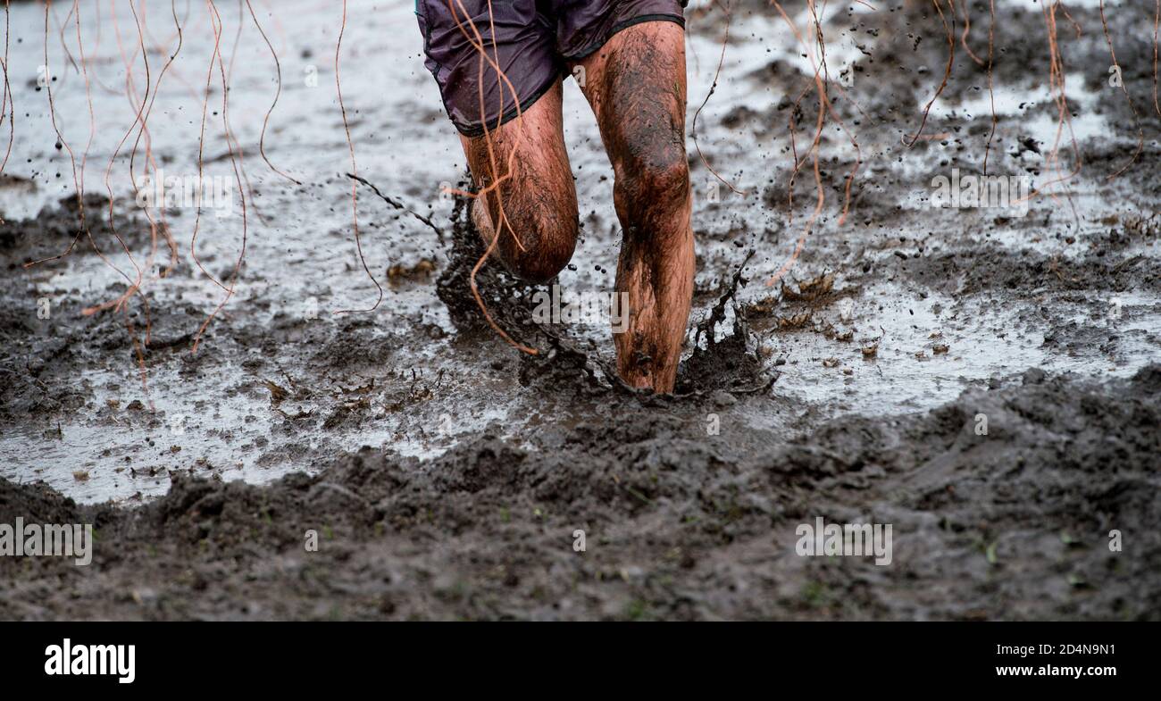 Mud race runner, man running in mud. Runners during extreme obstacle races. Active life and sport concept Stock Photo