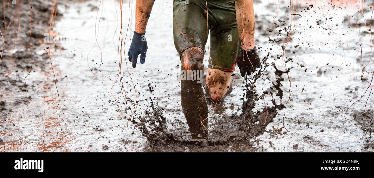 Mud race runner, man running in mud. Runners during extreme obstacle