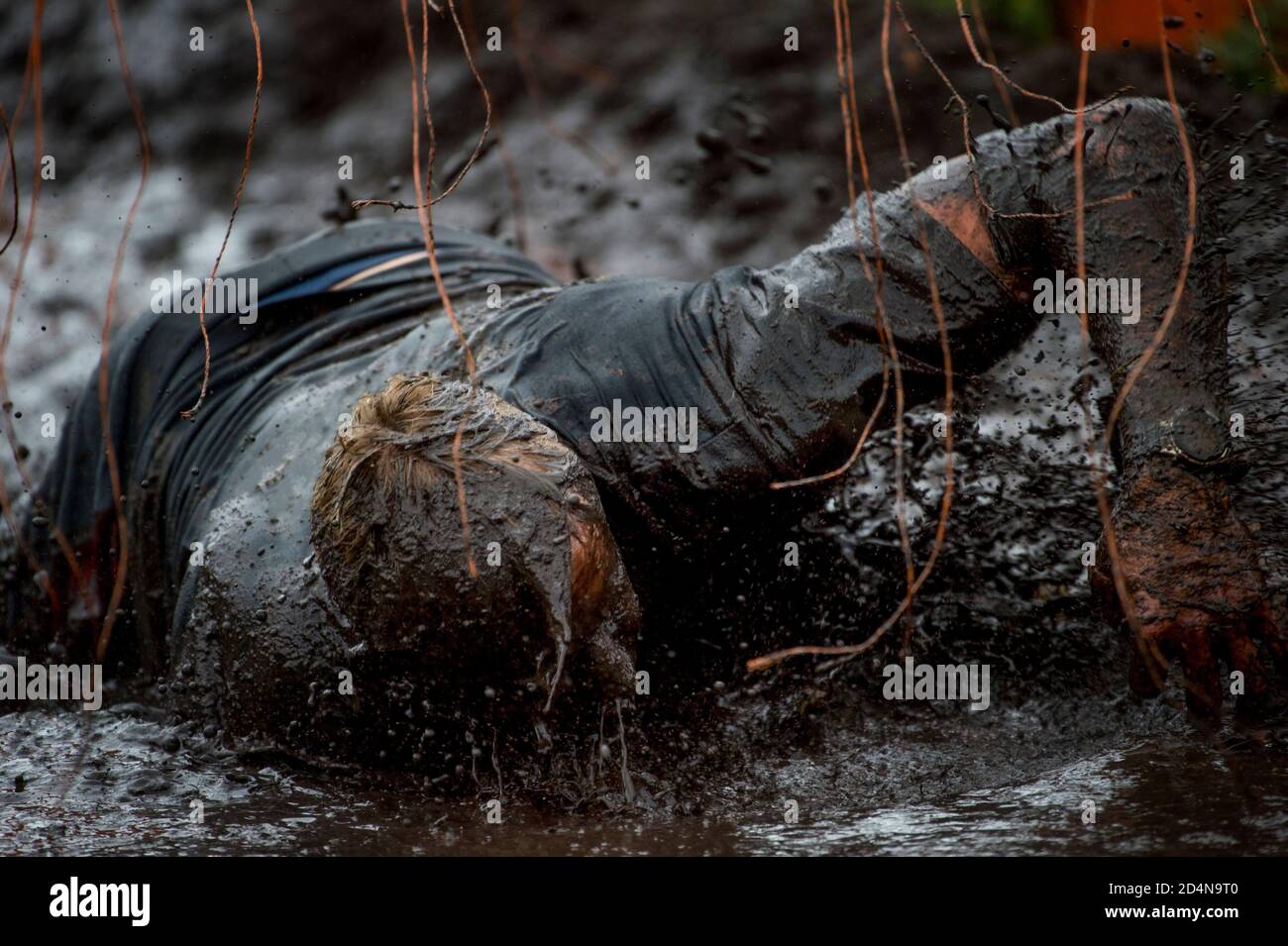 Mud race runner, man running in mud. Runners during extreme obstacle races. Active life and sport concept Stock Photo