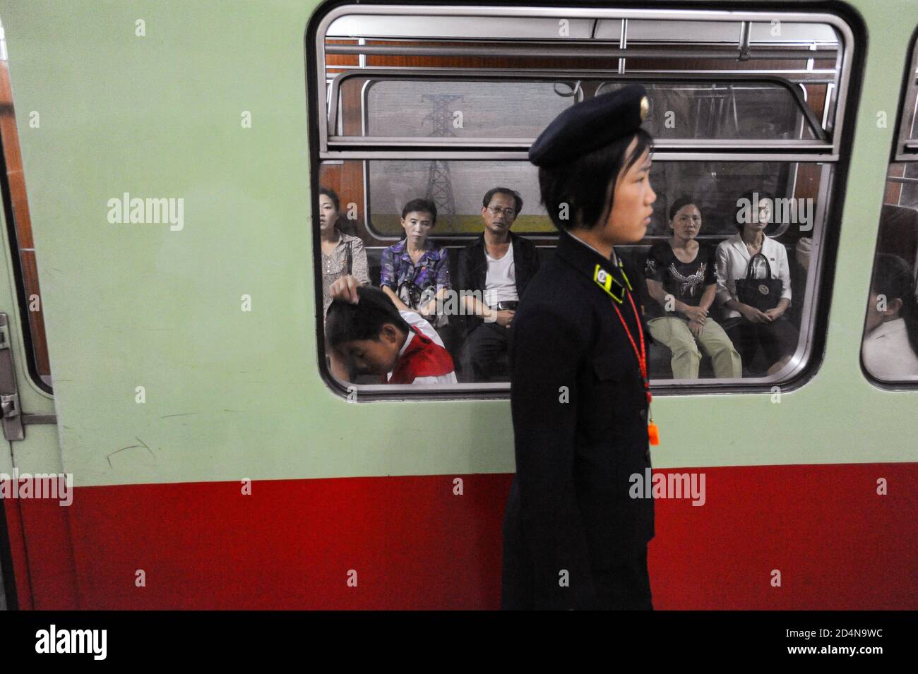 09.08.2012, Pyongyang, North Korea, Asia - A platform attendant stands in front of a subway train of the Pyongyang Metro with waiting commuters inside. Stock Photo