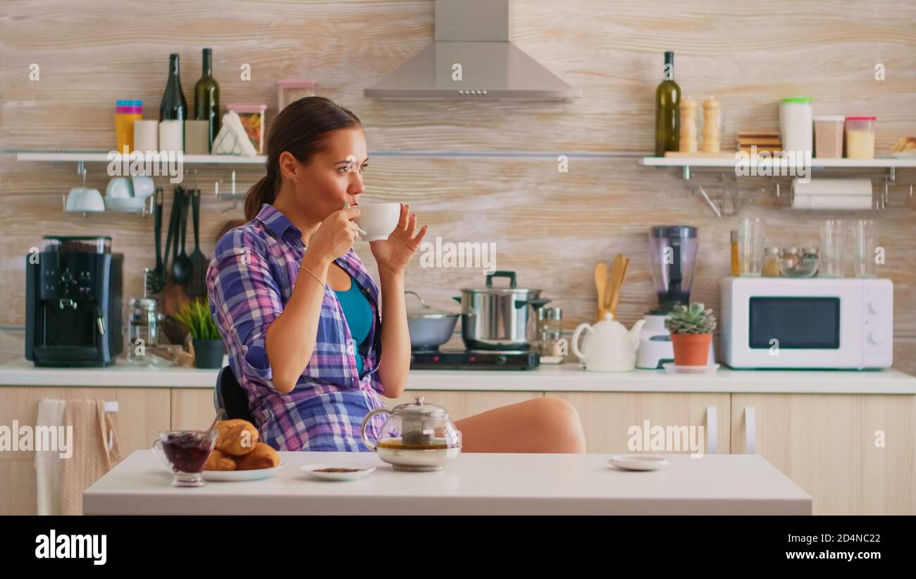 Pretty Lady Drinking Green Tea In The Kitchen Young Woman Relaxing Sitting In Modern Kitchen Near The Table In The Morning Enjoying Tasty Natural Herbal Tea From White Teacup Stock Photo