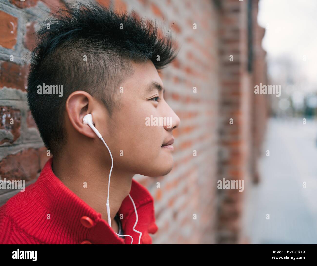 Portrait of young Asian boy listening to music with earphones outdoors in the streetl. Urban concept. Stock Photo