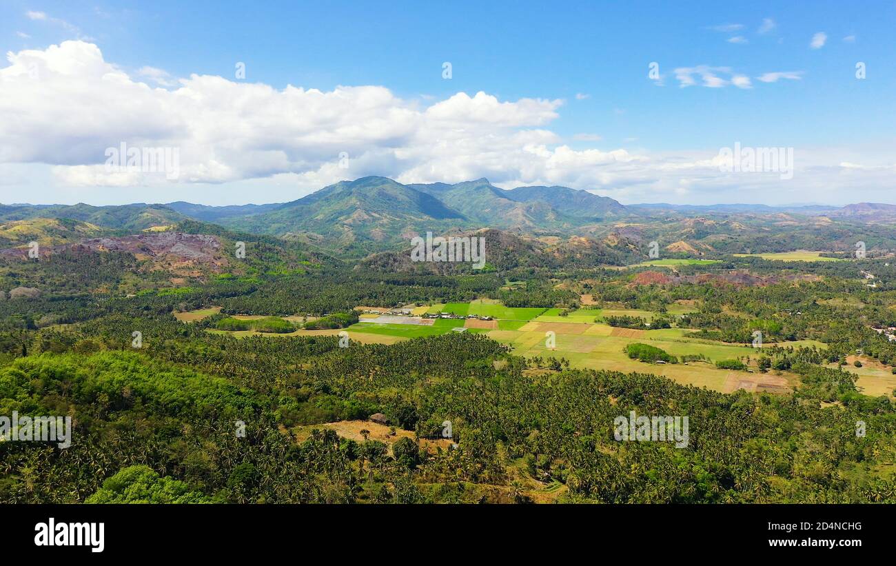 Fertile farmlands with growing crops and mountains with clouds against