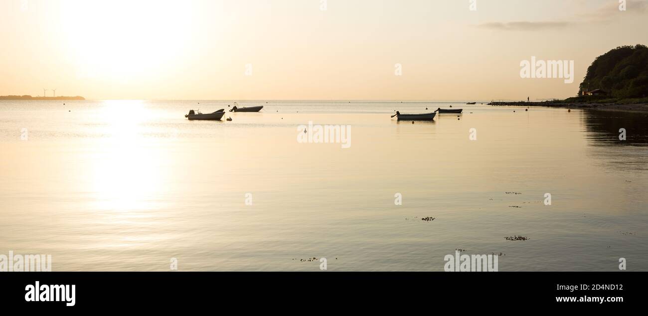 Beautiful sunrise over the calm Baltic sea with small boats in Westerholz, Germany Stock Photo