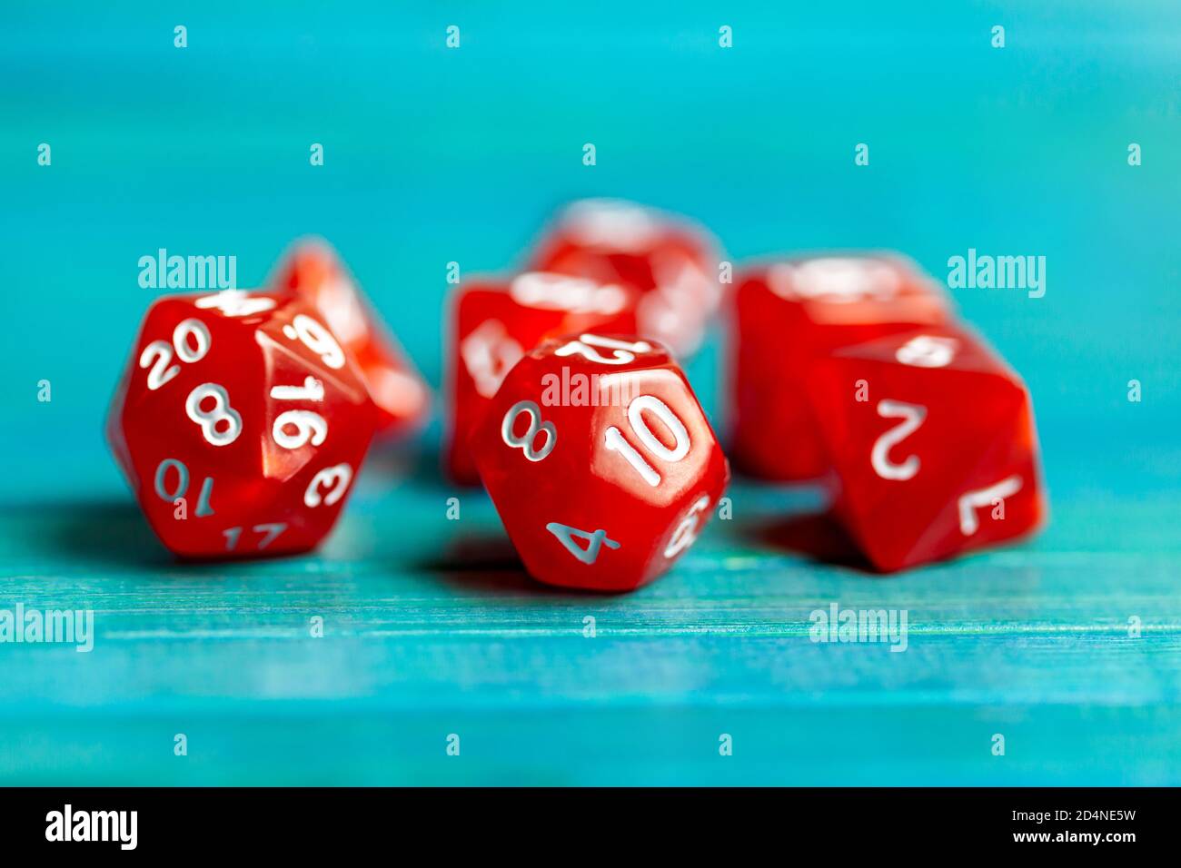 Simple red RPG board game dice set. Multiple role playing game polyhedral dice laying on the table, blue background. Tabletop games accessories Stock Photo