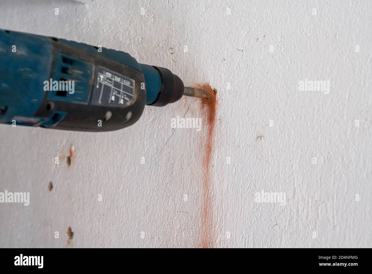 A worker is drilling a hole in the wall with a percussion drill Stock Photo