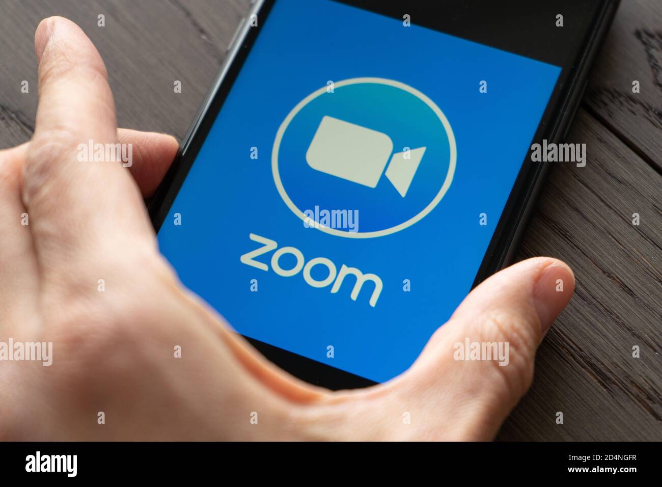 Phone with a hand showing Zoom Cloud Meetings app. Work and have