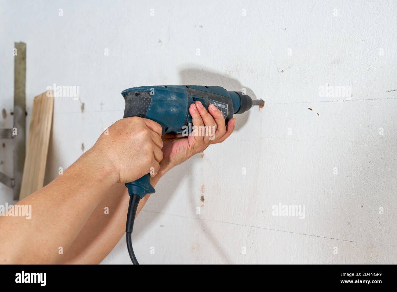 A worker is drilling a hole in the wall with a percussion drill Stock Photo