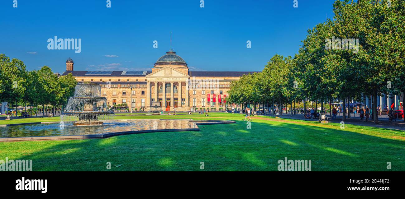 Wiesbaden, Germany, August 24, 2019: panorama of Kurhaus or cure house spa and casino building and Bowling Green park with grass lawn, trees alley and pond with fountain in historical city centre Stock Photo