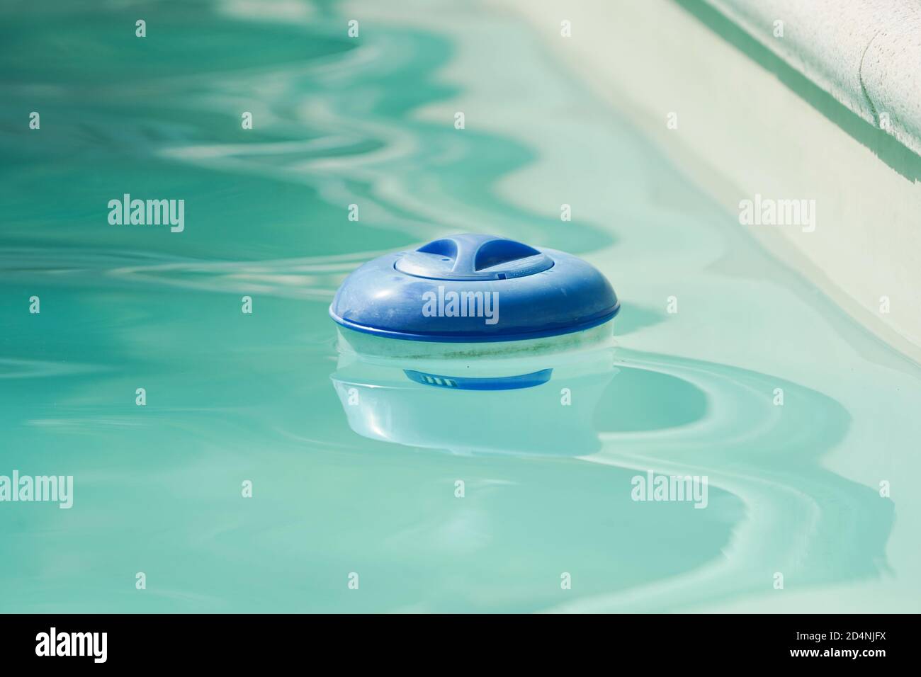 Chlorine container floating in a swimming pool. Spain. Stock Photo