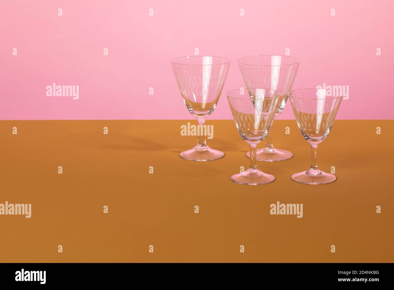 Set of classsic martini cocktail glasses standing on a brown surface and a pink colored background. Clean minimalistic elegant style Stock Photo