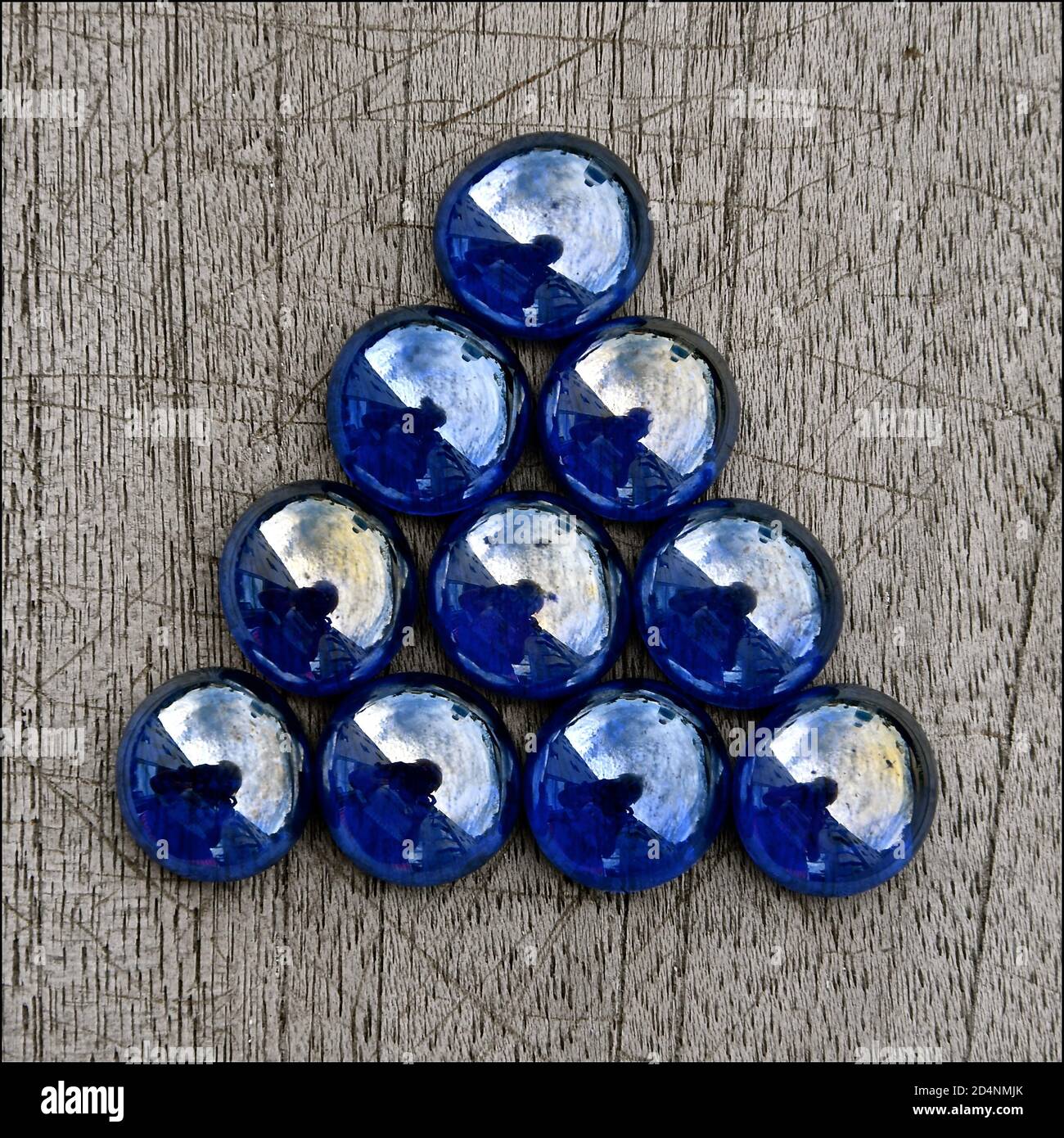 Triangle of iridescent blue glass beads isolated on a rustic wooden background Stock Photo