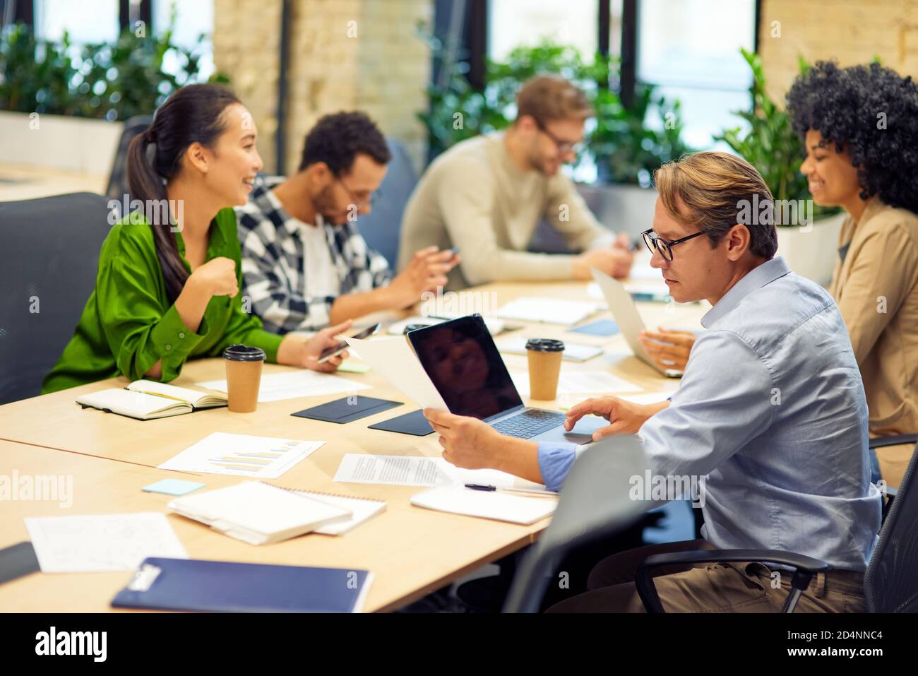 Business meeting. Group of multiracial people sitting at the desk in the modern coworking space or office and working on project together. Teamwork and collaboration, business concept Stock Photo