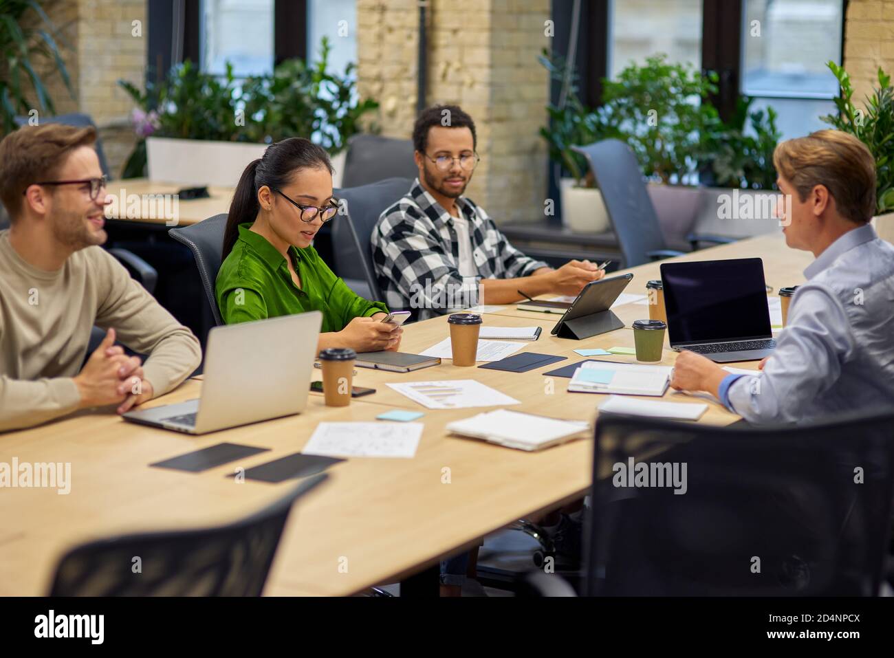 Group of young multiracial business people sitting at desk in the board room and working on project together, discussing work and sharing ideas. Teamwork, collaboration and business Stock Photo