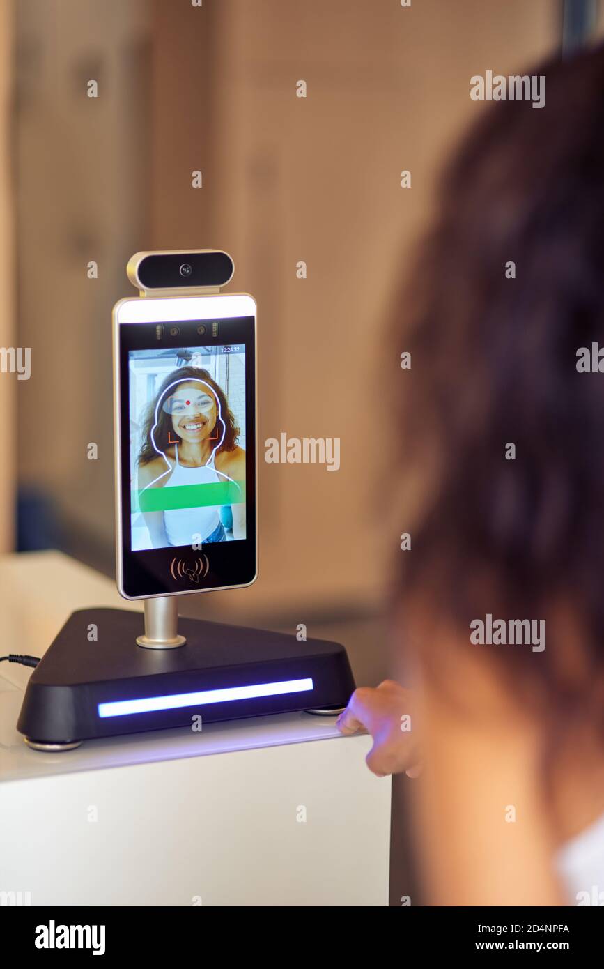 Modern security system. Rear view of female office worker using face recognition at work, business and identification technology Stock Photo