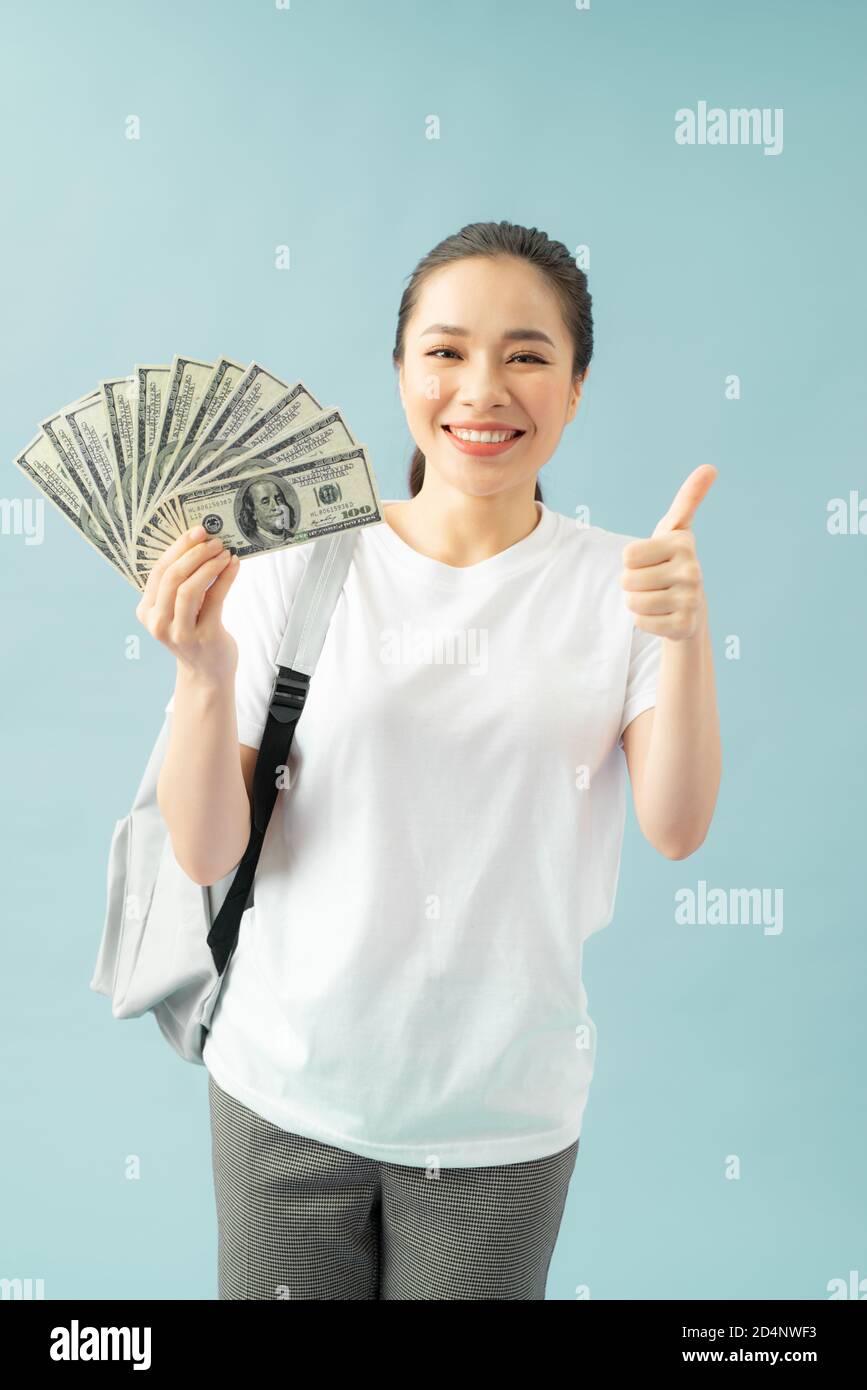 Funny girl student wearing backpack isolated, holding fan of cash money
