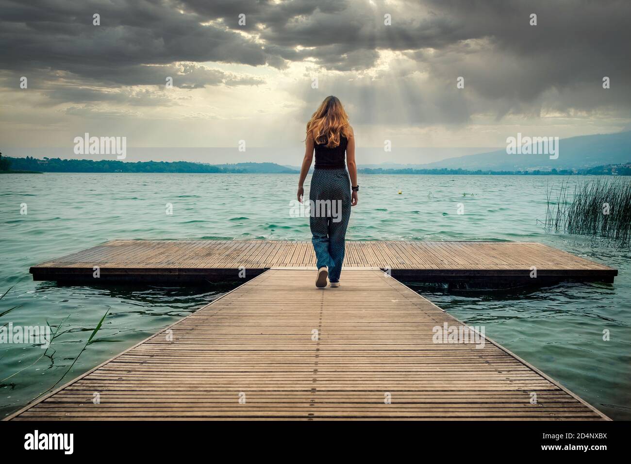 Young girl modeling on the quay looking in front of the camera, Lake of Pusiano, Lecco, Italy Stock Photo